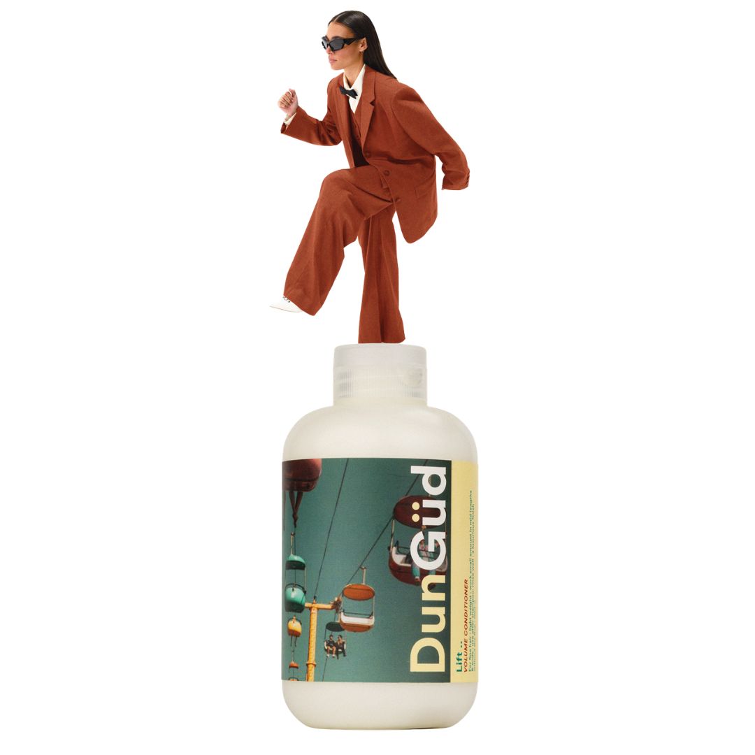 Person in a suit standing on top of a DunGüd bottle with a scenic label.