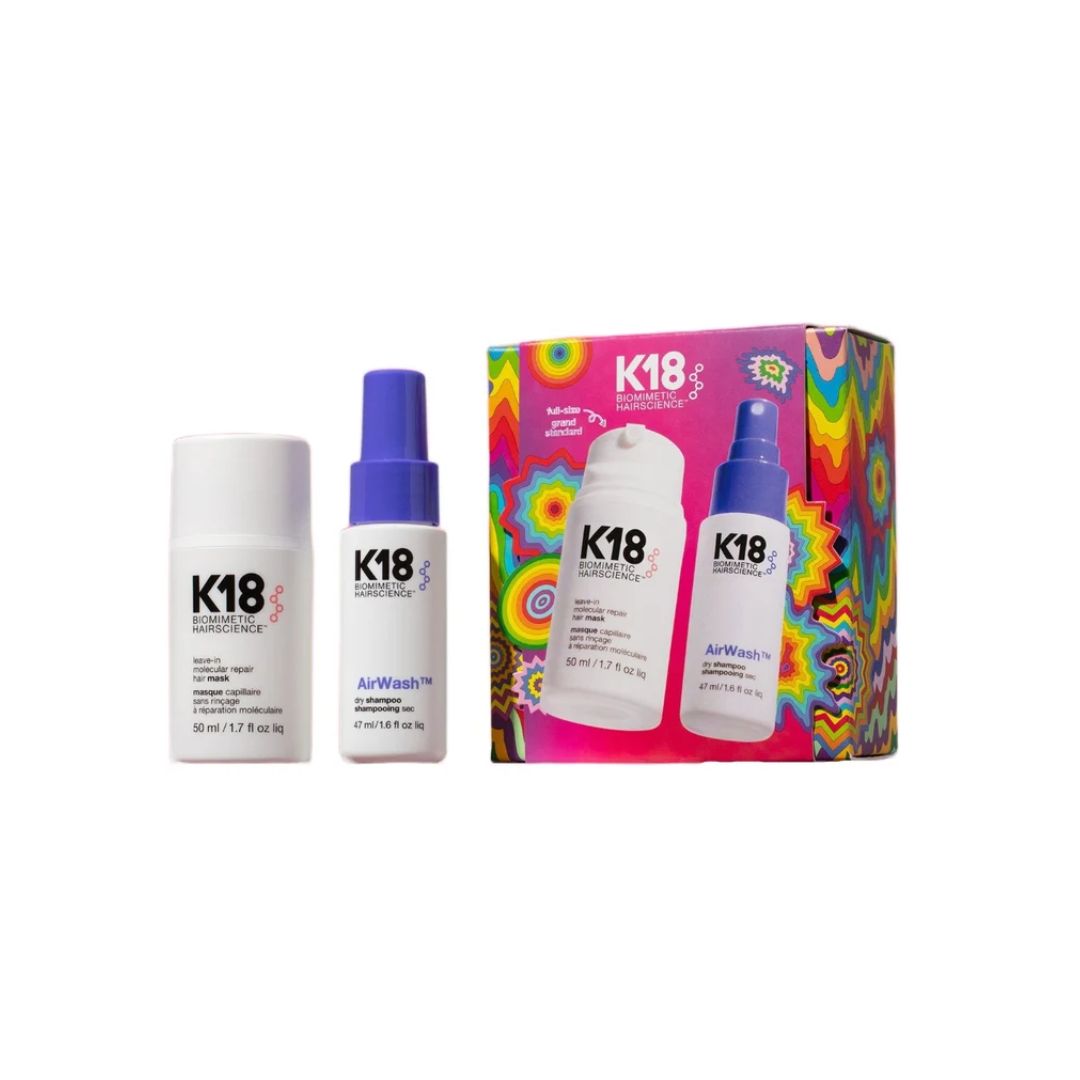 K18 hair care set featuring a white hair building rodent, a white AirWash bottle with a blue spray top, and a colorful box with a psychedelic pattern showing the same products.