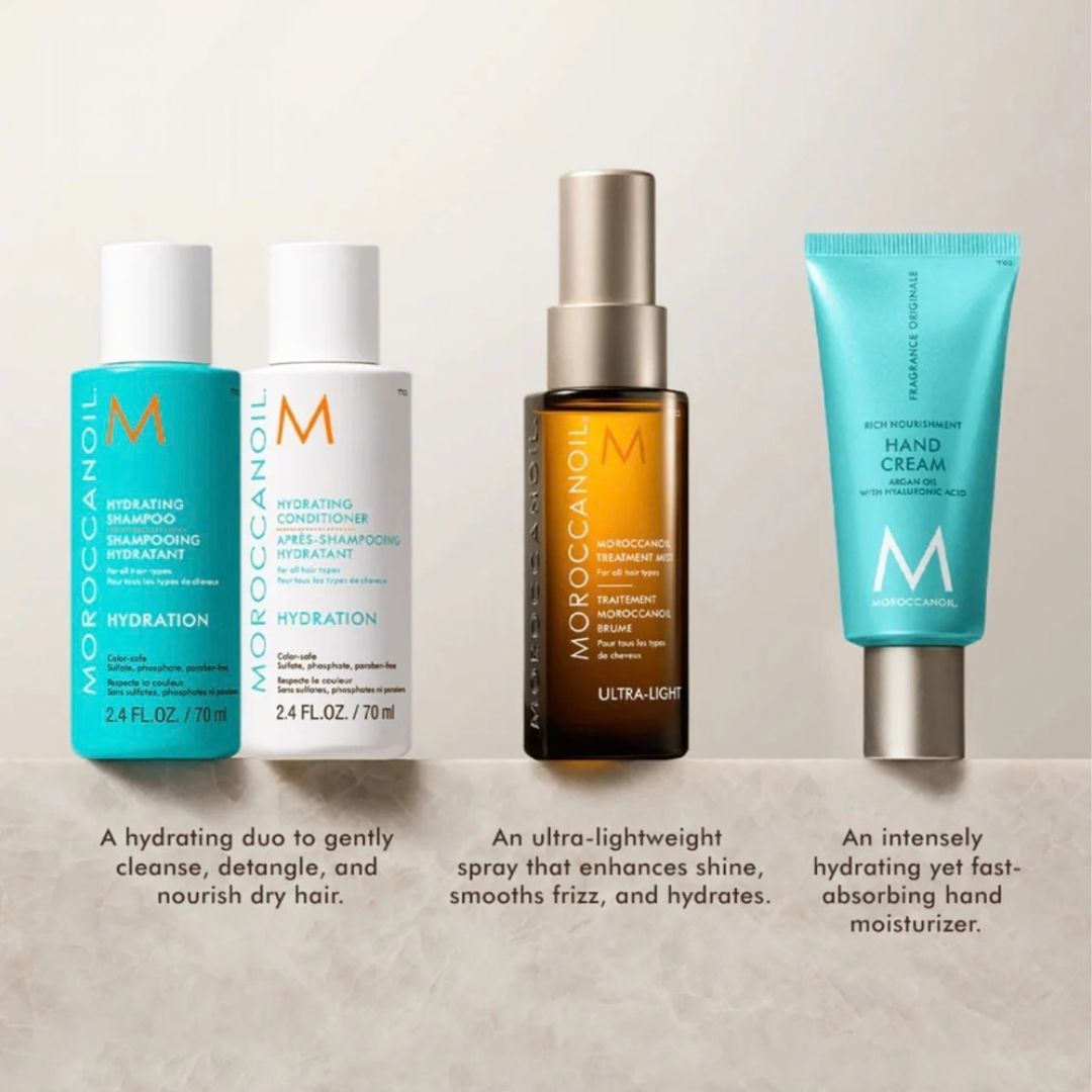 Four Moroccan Oil hair care products arranged on a light beige background: a turquoise shampoo bottle, a white conditioner bottle, an amber spray bottle with a silver cap, and a turquoise hand cream tube. Text below each product describes its hydrating benefits.