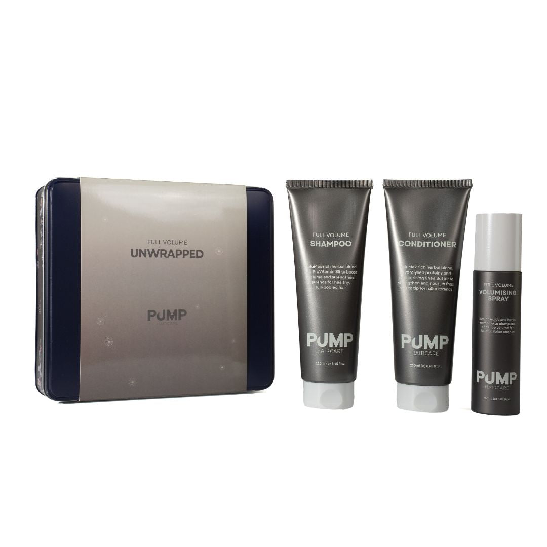 PUMP Full Volume Unwrapped hair care set featuring a gray and navy blue zippered case, a tube of shampoo, a tube of conditioner, and a spray bottle, all on a white background.
