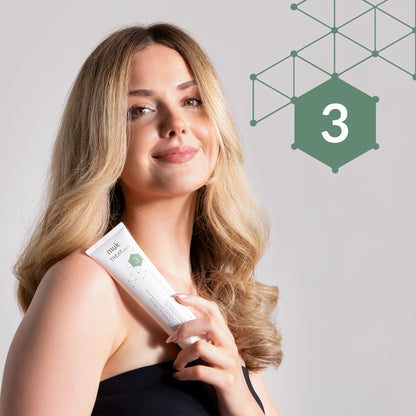 Woman holding a white tube with green hexagonal logo and number 3 on a light gray background