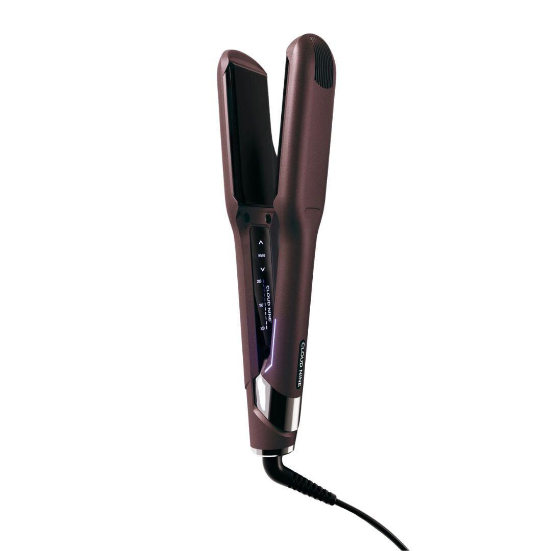 A hair straightener with a metallic dark plum-brown finish, featuring a digital temperature display on the side and a black cord extending from the bottom, set against a plain white background.