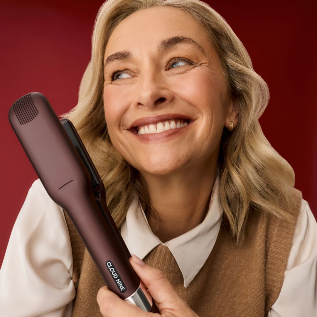 Woman holding a hair straightener with a red background