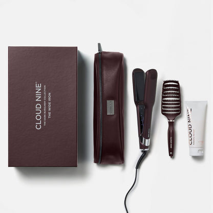 Cloud Nine The Wide Icon hair styling set on a light gray background, including a dark brown presentation box, a zippered case, a flat iron, a round brush, and a small tube.