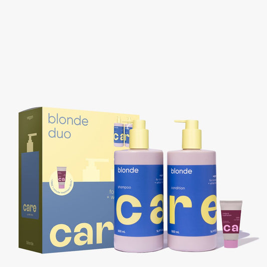 Care for Color blonde duo set featuring a large box, two large bottles of shampoo and conditioner with pale pink bodies and blue labels, and a small tube, all on a clean white background.