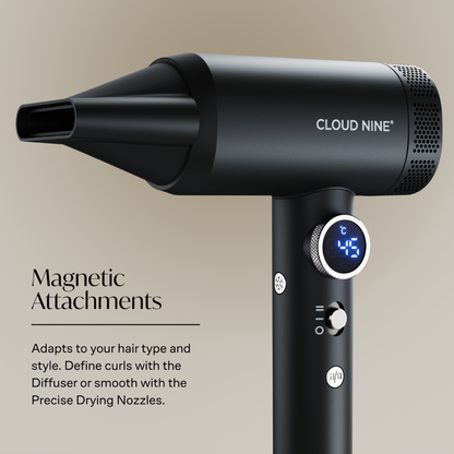 Black Cloud Nine hair dryer with a concentrator nozzle, digital temperature display, and control buttons, shown with text highlighting magnetic attachments on a warm beige background.