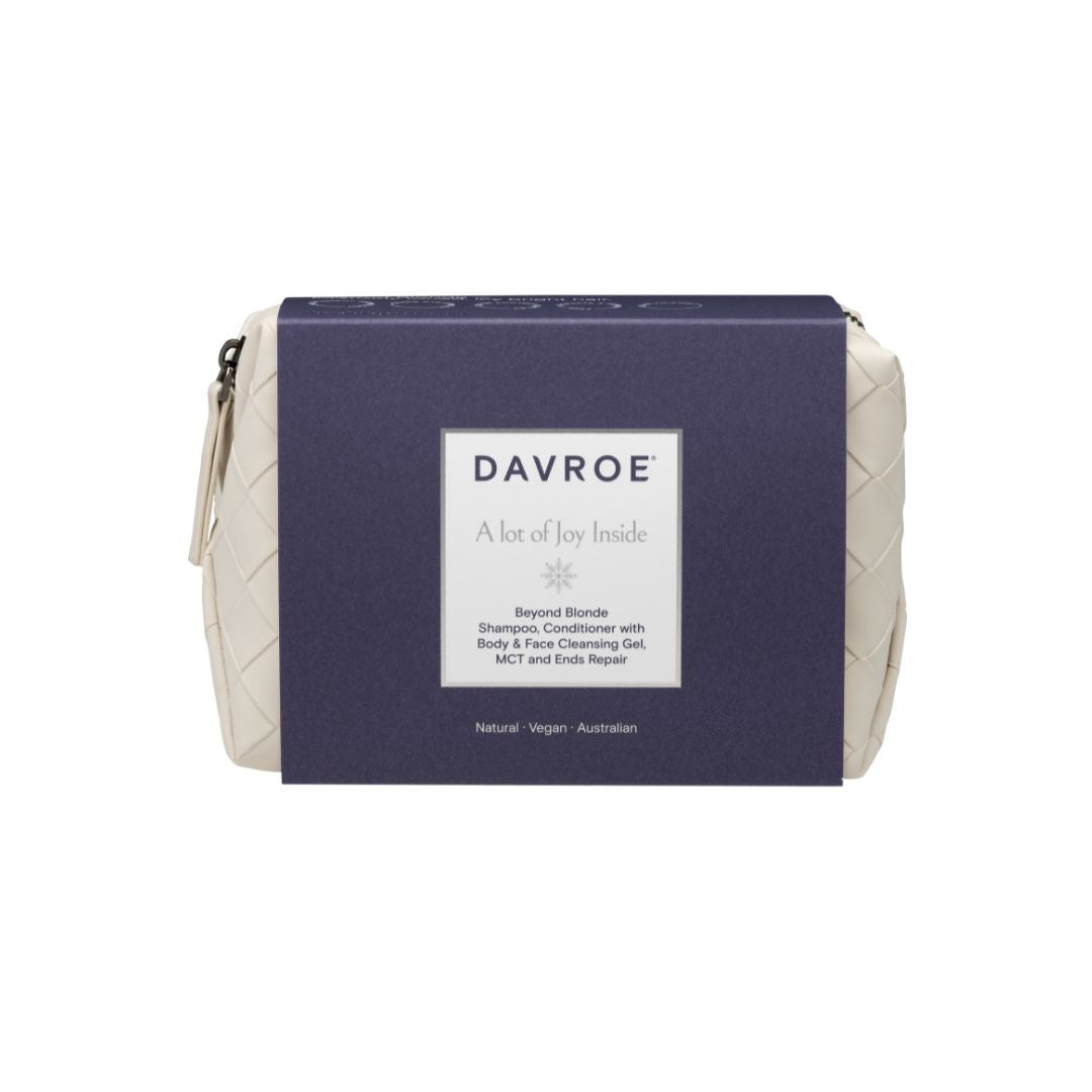 A white quilted cosmetic pouch by Davroe, shown closed with its navy blue cardboard packaging sleeve in the center. The packaging features a white label with the brand name 'DAVROE' and product details.