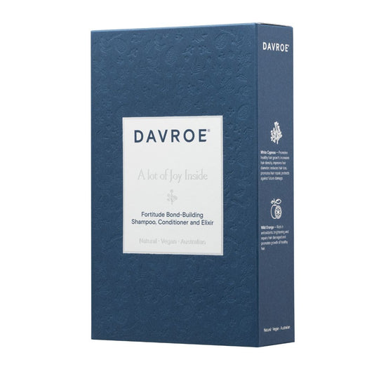 A tall rectangular blue box for Davroe Fortitude Bond-Building Shampoo, Conditioner and Elixir, shown on a plain white background. The front has a white label with the brand name and product details, and the side panel shows additional text and icons.