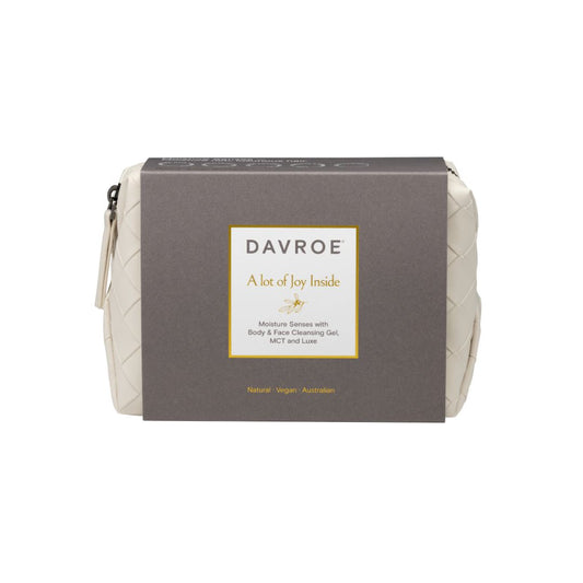 A Davroe 'A lot of joy inside' body and face cleansing gel pouch, featuring a dark brown cardboard sleeve with a white and gold label, set against a plain white background.