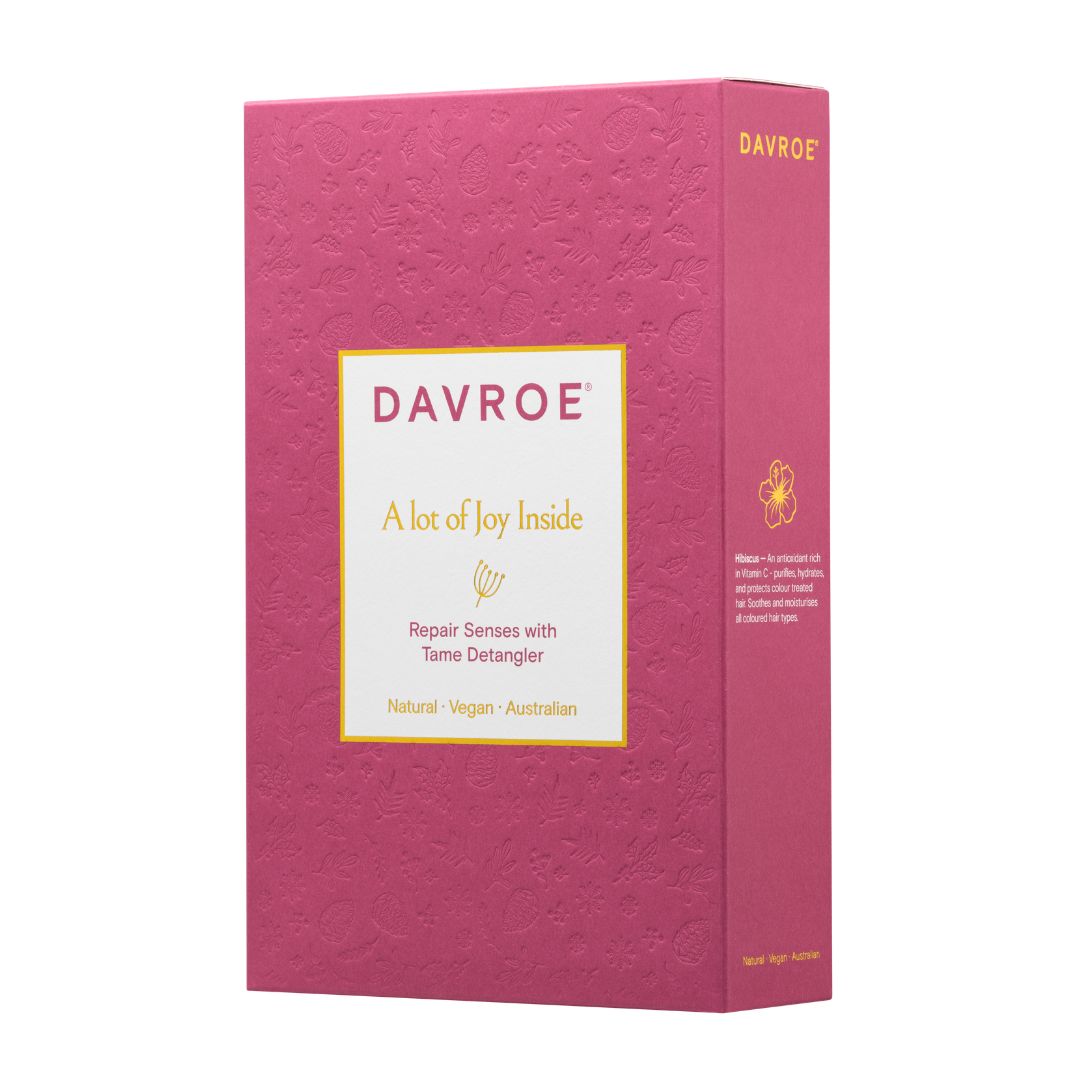 A pink textured box for Davroe Tams Detangler, featuring a white label with gold text and a small tams illustration, shown on a plain white background.