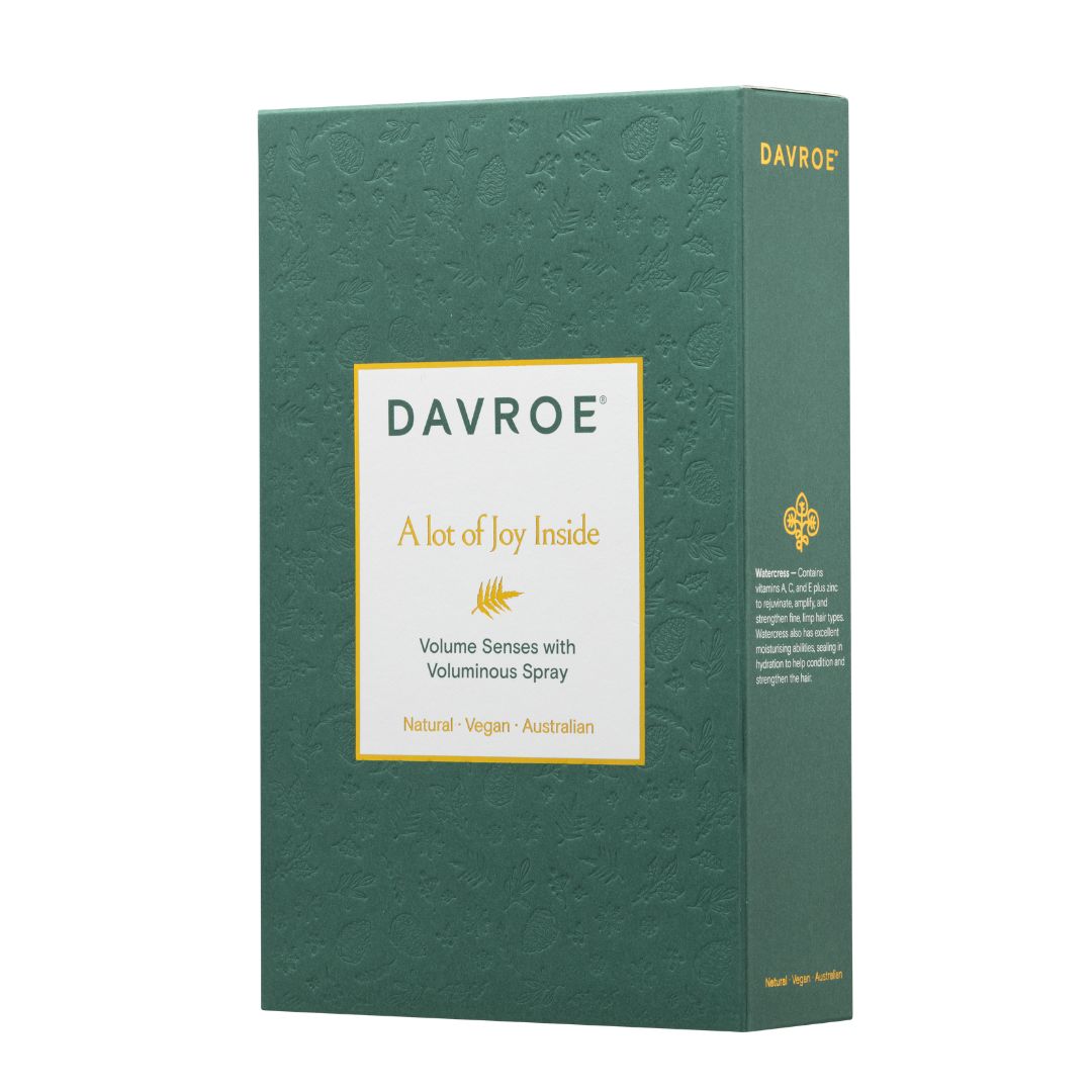 A rectangular green product box for DAVROE Voluminous Spray, featuring a textured embossed pattern, a white label with gold and green text, and gold lettering on the side panel, set against a plain white background.