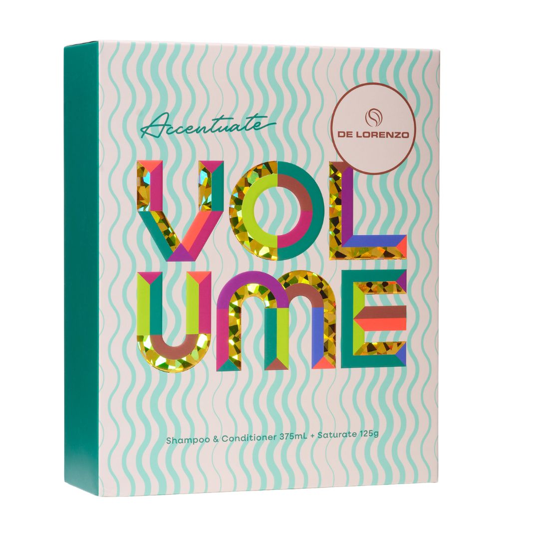 A rectangular product box for De Lorenzo Acentuate Volume Shampoo & Conditioner, featuring a pastel wavy pattern background with large, colorful, patterned letters spelling 'VOLUME' and a teal spine.