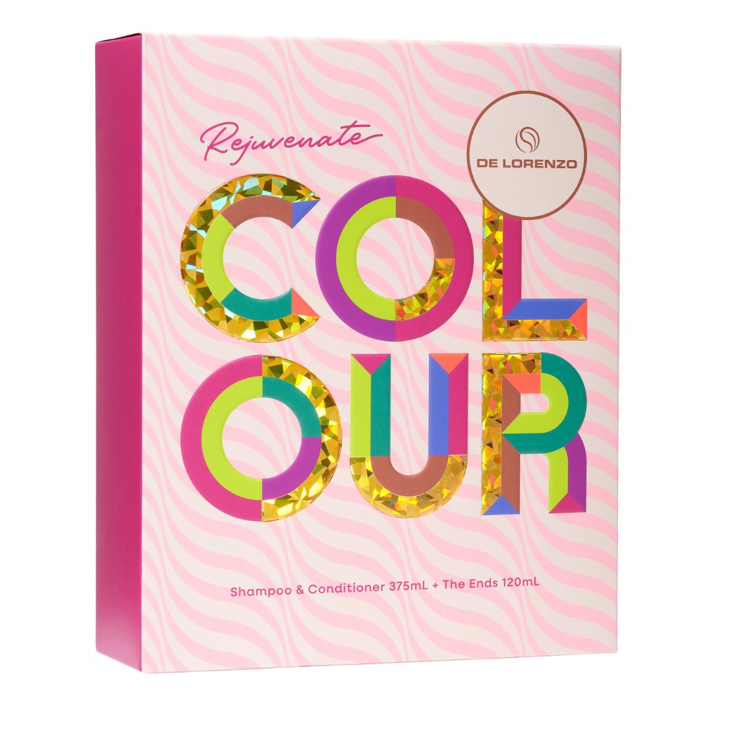 A pink rectangular product box for De Lorenzo Rejuvenate Colour Shampoo & Conditioner. The box features a pink and white wavy pattern background, a solid pink spine, and large, colorful, glitter-filled letters spelling 'COLOUR'.