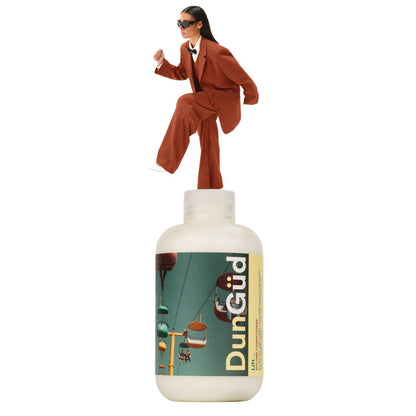 Person in a suit standing on top of a DunGüd bottle with a scenic label.