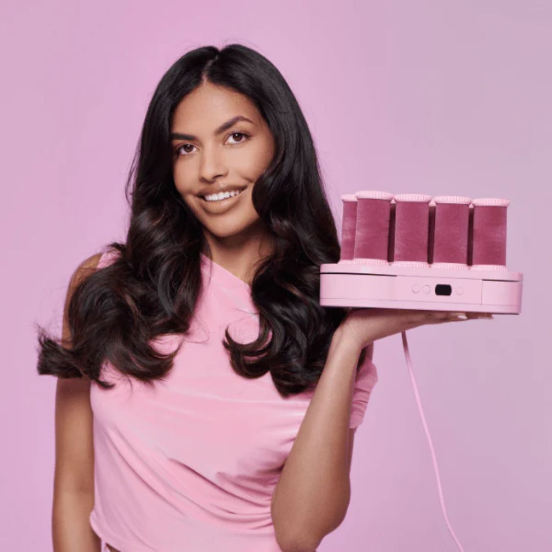 Woman holding pink hair extensions against a pink background