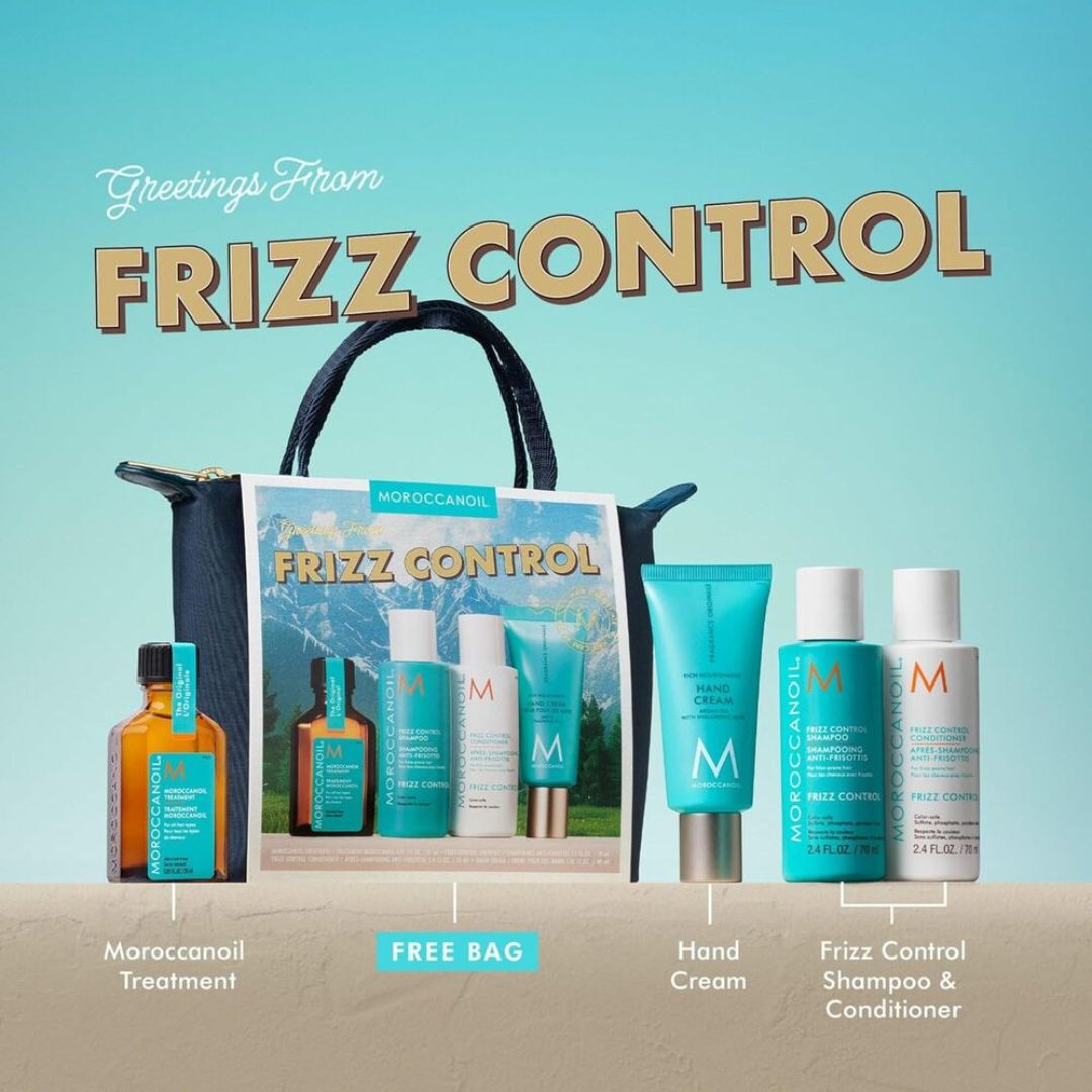 Moroccanoil Frizz Control gift set featuring a black tote bag, a bottle of amber-colored treatment, a free bag, hand cream, and shampoo and conditioner bottles, arranged on a light blue background with the text 'Greetings From FRIZZ CONTROL'.