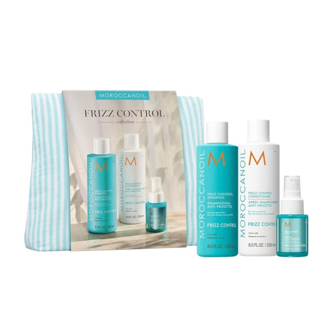 Moroccanoil Frizz Control collection hair care set including a striped zip pouch, shampoo, conditioner, styling foam, and a small spray bottle, shown on a white background.