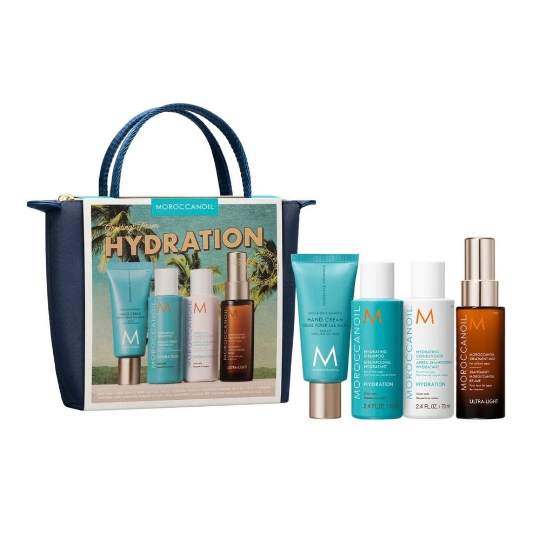 Moroccanoil Hydration gift set featuring a navy blue tote bag with a printed tropical illustration and five skincare bottles and tubes arranged in front on a white background.