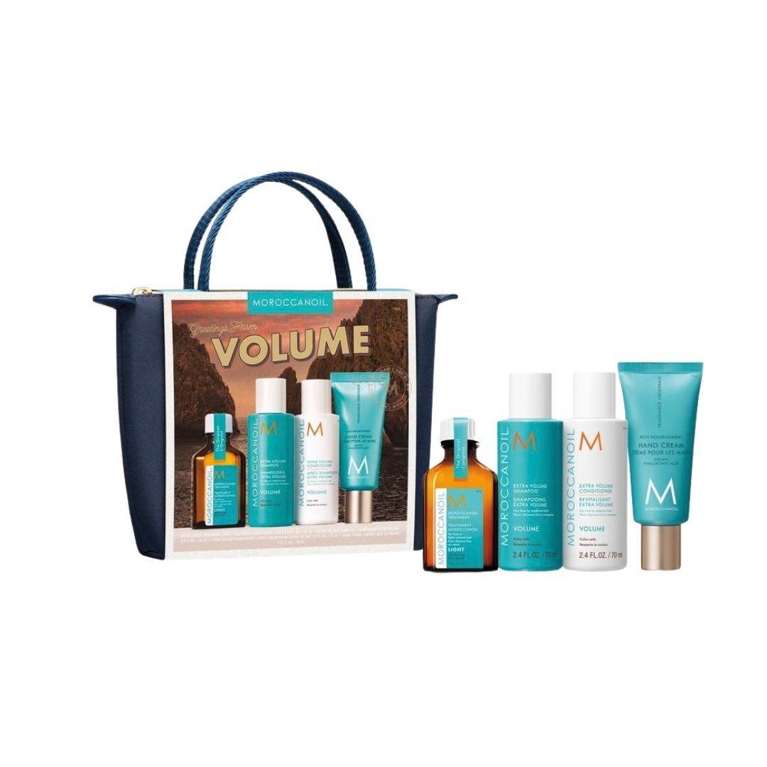 Moroccanoil Volume hair care gift set featuring a navy blue tote bag with a printed insert and six haircare products (two amber bottles, two white bottles, and two teal tubes) displayed on a clean white background.