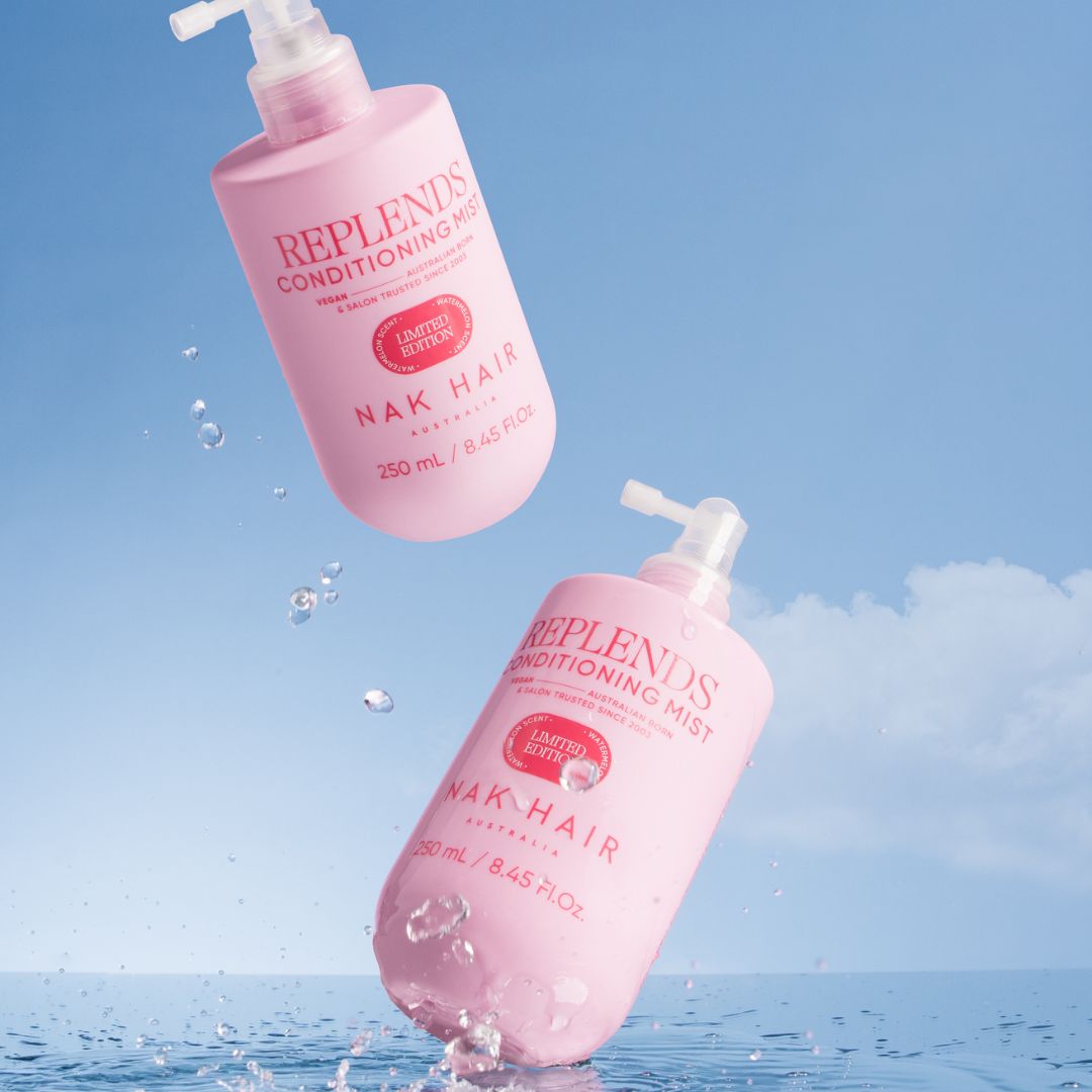Two pink bottles of Replends Conditioning Mist with Nak Hair on a blue water background