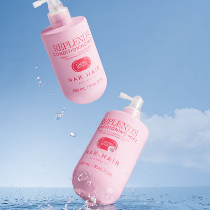 Two pink bottles of Replends Conditioning Mist with Nak Hair on a blue water background