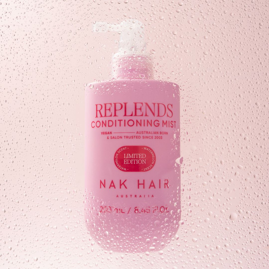 Pink bottle of Replends Conditioning Mist by Nak Hair on a textured pink background
