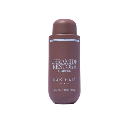 A bottle of NAK HAIR Ceramide Restore Shampoo in a matte dark brown color, shown against a plain white background.