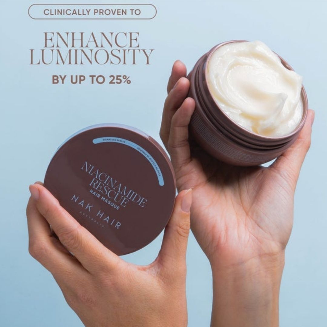 Two hands holding open and closed jars of Nak Hair Niacinamide Rescue Hair Masque against a light blue background with promotional text.