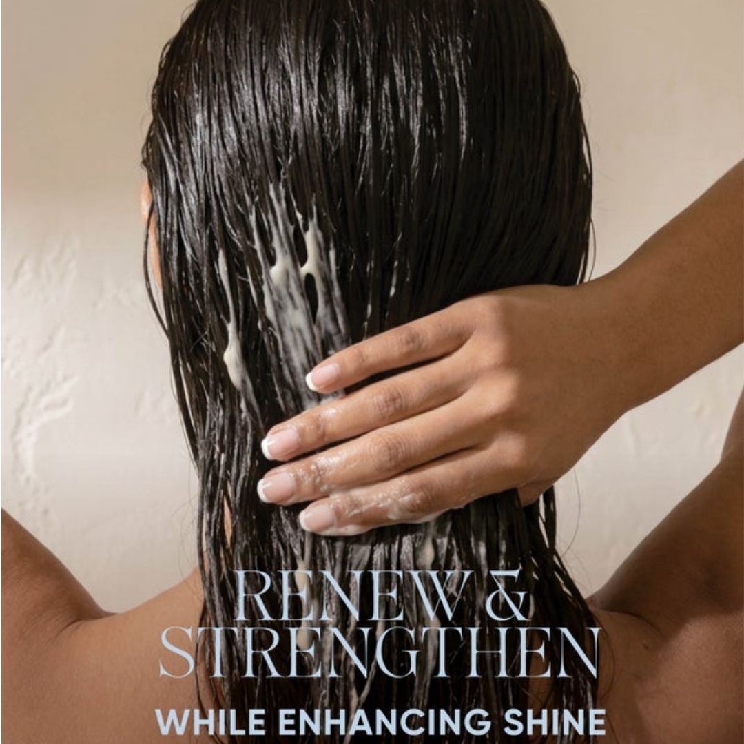 Back view of a person with long, dark, wet hair lathered with shampoo, with a hand gently touching the hair. Text overlay reads 'RENEW & STRENGTHEN WHILE ENHANCING SHINE'.