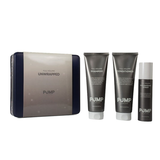 PUMP Full Volume Unwrapped hair care set featuring a gray and navy blue zippered case, a tube of shampoo, a tube of conditioner, and a spray bottle, all on a white background.