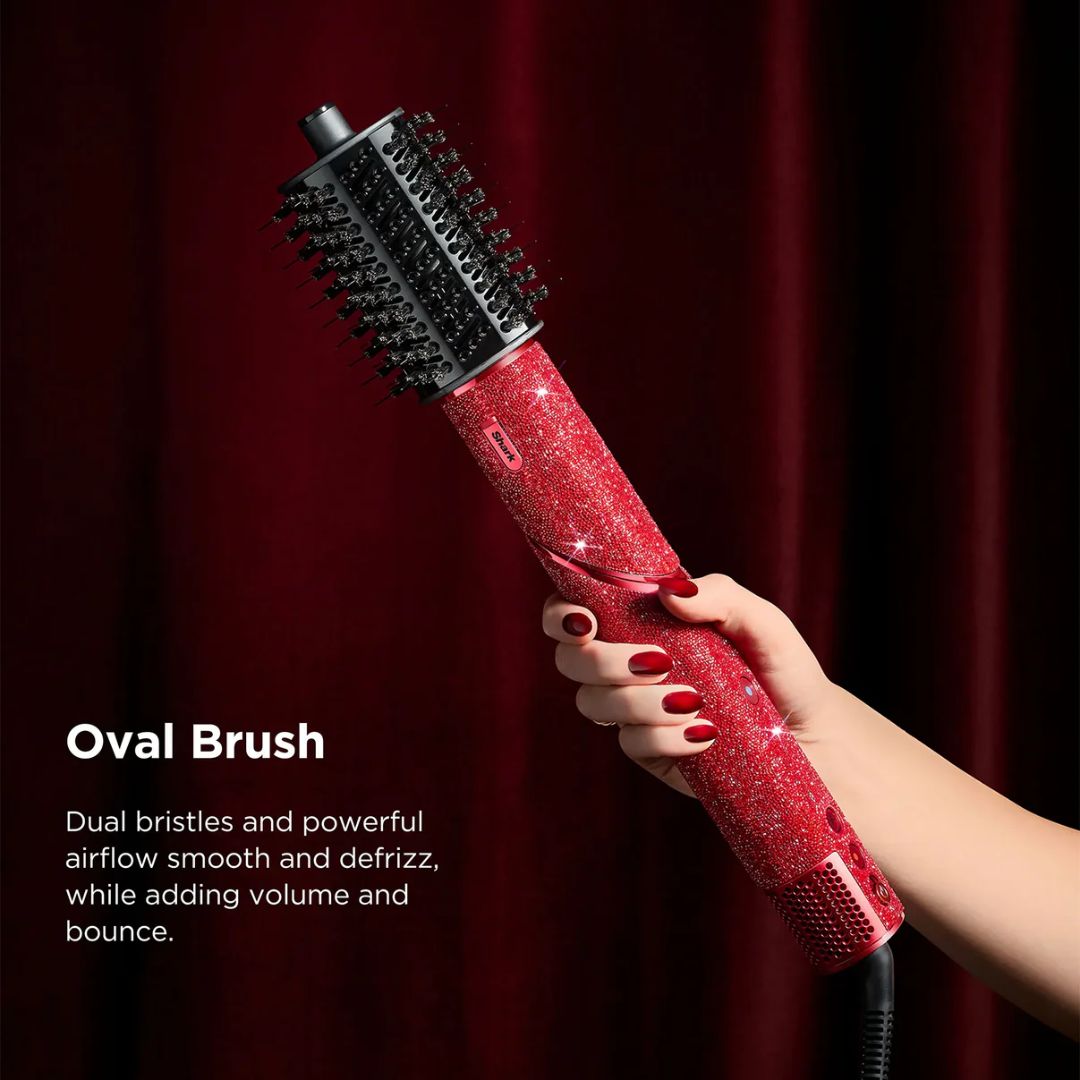 Red oval brush with black bristles held by a hand against a red curtain background