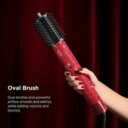 Red oval brush with black bristles held by a hand against a red curtain background
