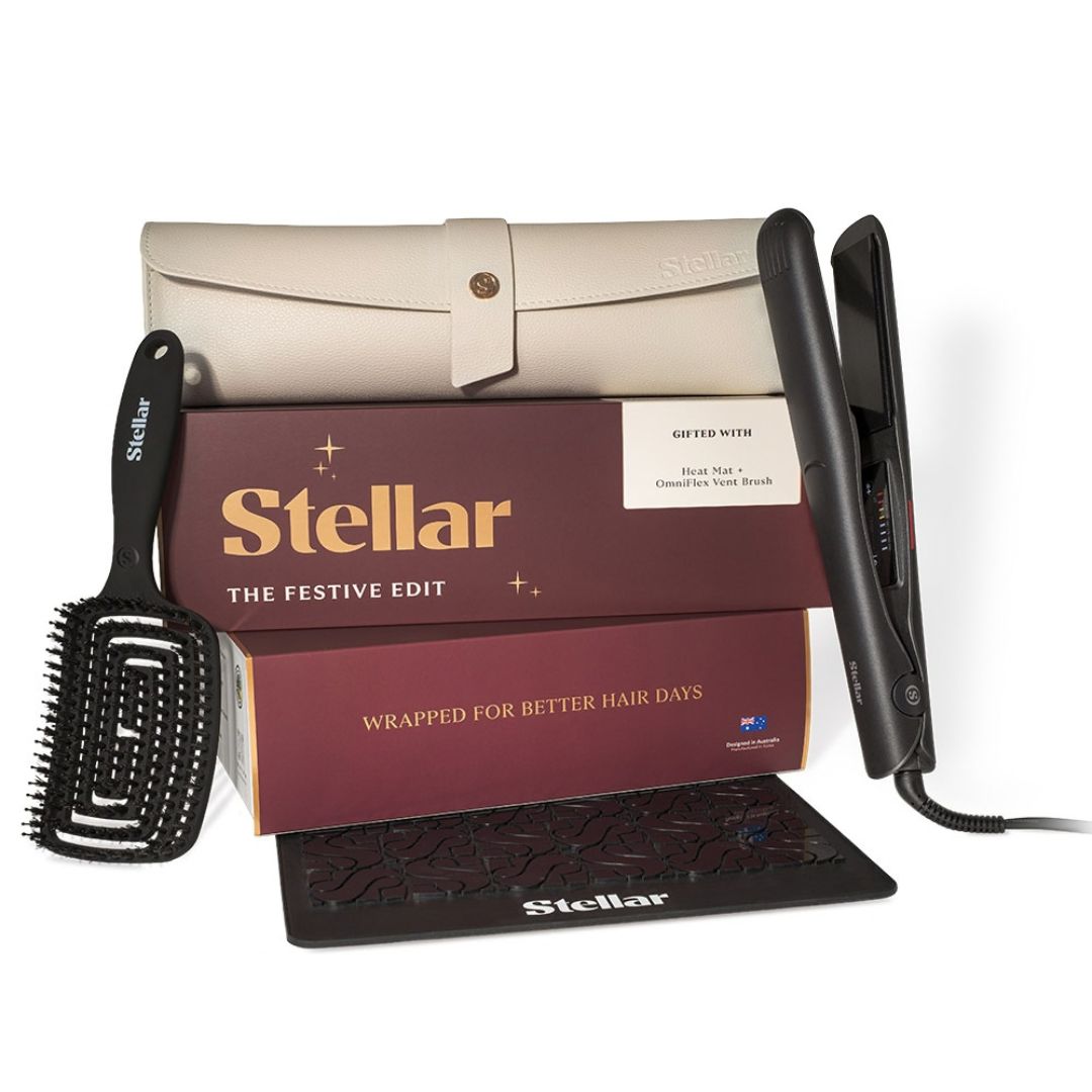 Stellar The Festive Edit haircare gift set featuring a black flat iron, black brush, cream-colored travel case, and two maroon gift boxes on a white background.