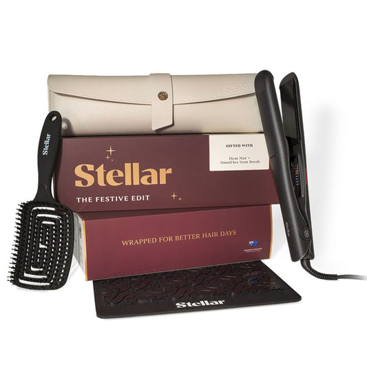 Stellar The Festive Edit haircare gift set featuring a black flat iron, black brush, cream-colored travel case, and two maroon gift boxes on a white background.