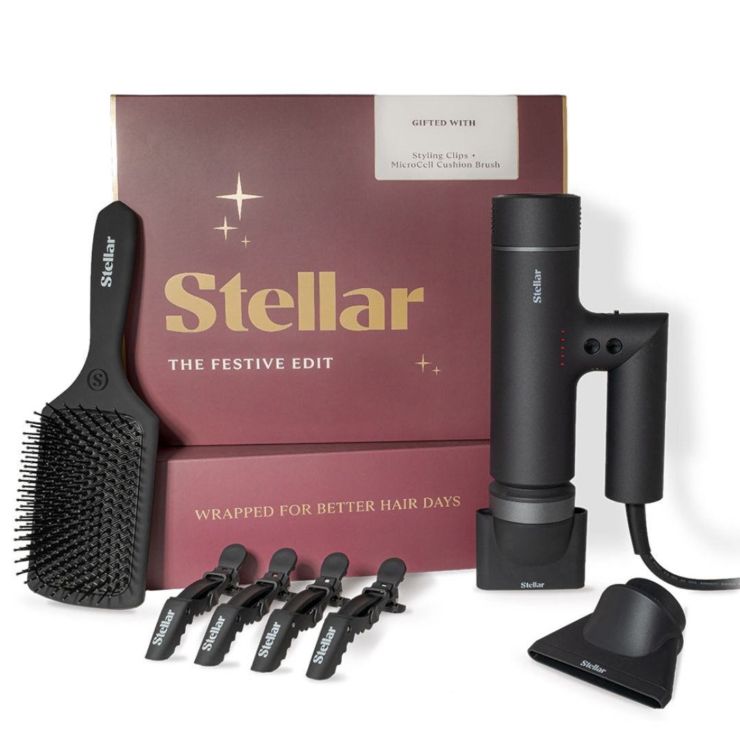 Stellar styling set gift box with a black styling brush, hair dryer, stand, and four black hair clips on a white background.