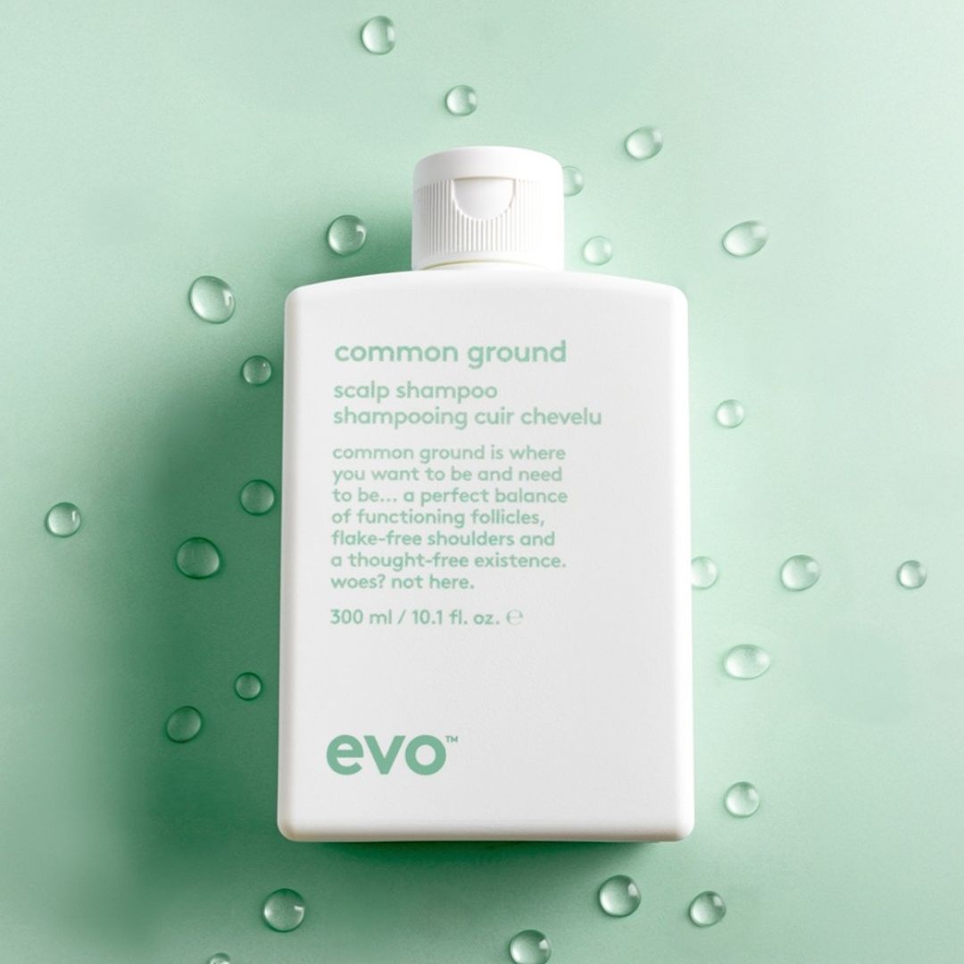 Evo common ground scalp shampoo bottle on a green background with water droplets.