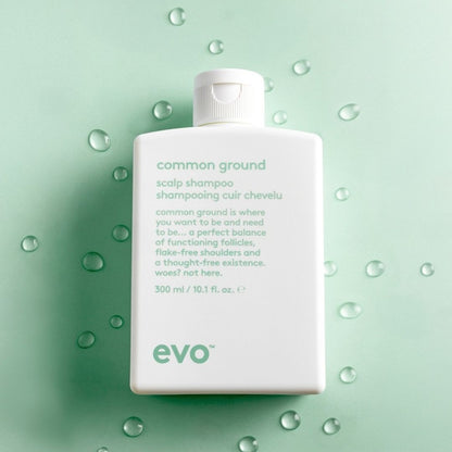 Evo common ground scalp shampoo bottle on a green background with water droplets.