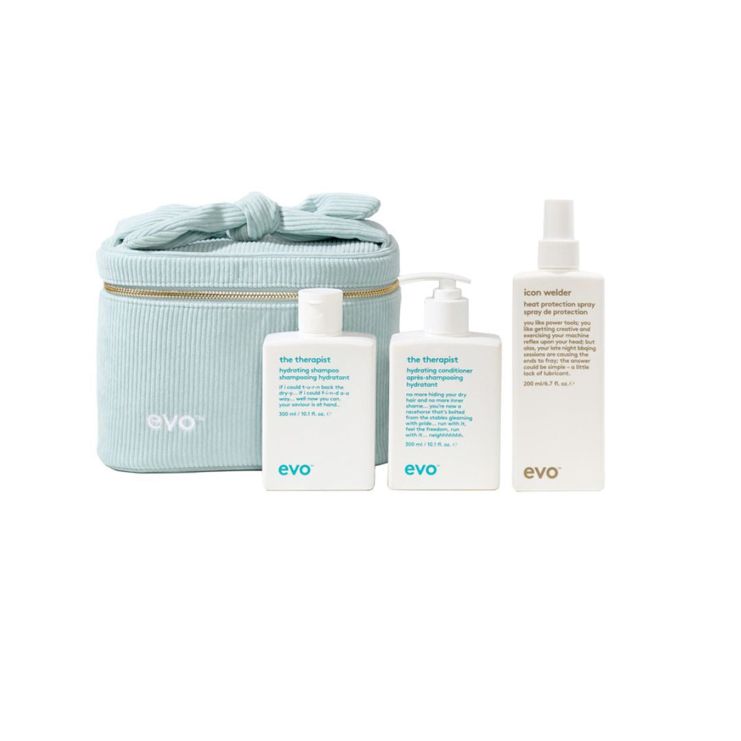 A skincare set from EVO featuring a light blue corduroy zippered pouch with a bow, alongside three white bottles: The Therapist hand wash, The Therapist hand lotion, and Icon visible hand deodorizer, all on a white background.