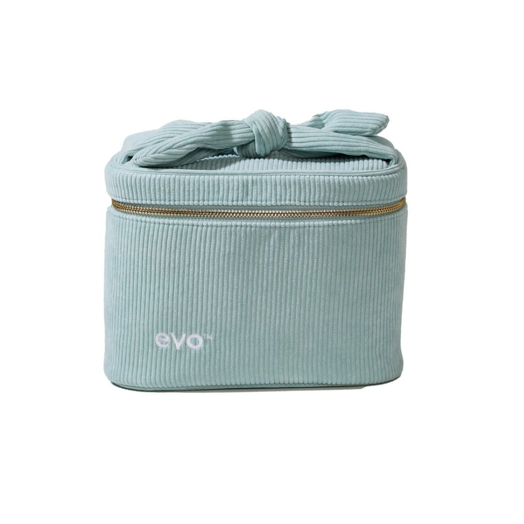 A light blue-green corduroy cosmetic bag with a matching fabric top handle tied in a bow, a gold zipper, and the 'evo' logo on the front, set against a plain white background.