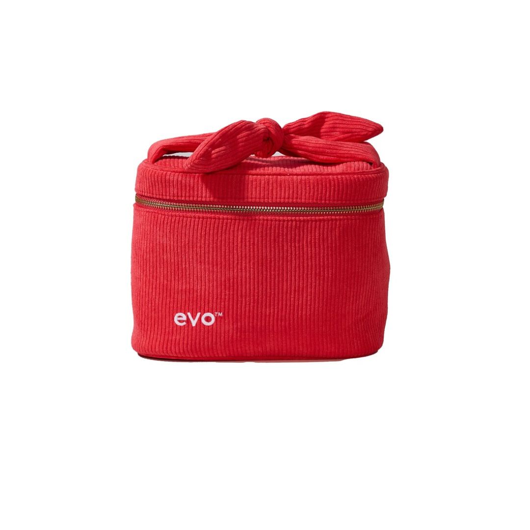 A red corduroy cosmetic bag with a top handle tied in a bow, featuring a gold zipper and the white 'evo' logo on the front, set against a plain white background.