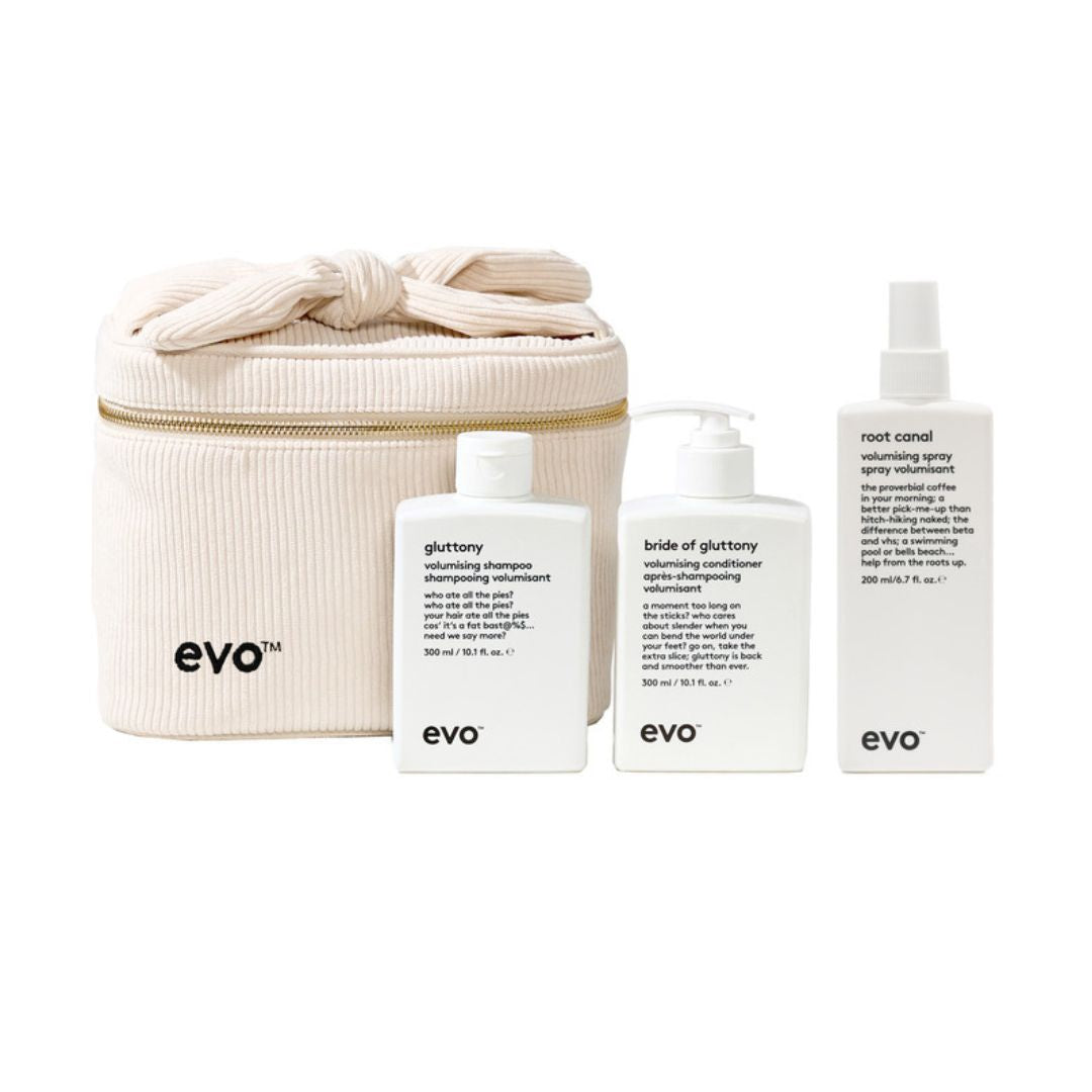 A set of three white EVO haircare bottles and a cream-colored zippered storage bag on a plain white background. The products include Glory shine shampoo, Bride of Gluttony volumining conditioner, and Root Canal volumining spray, with the brand name 'evo' printed in black on the bag and bottles.