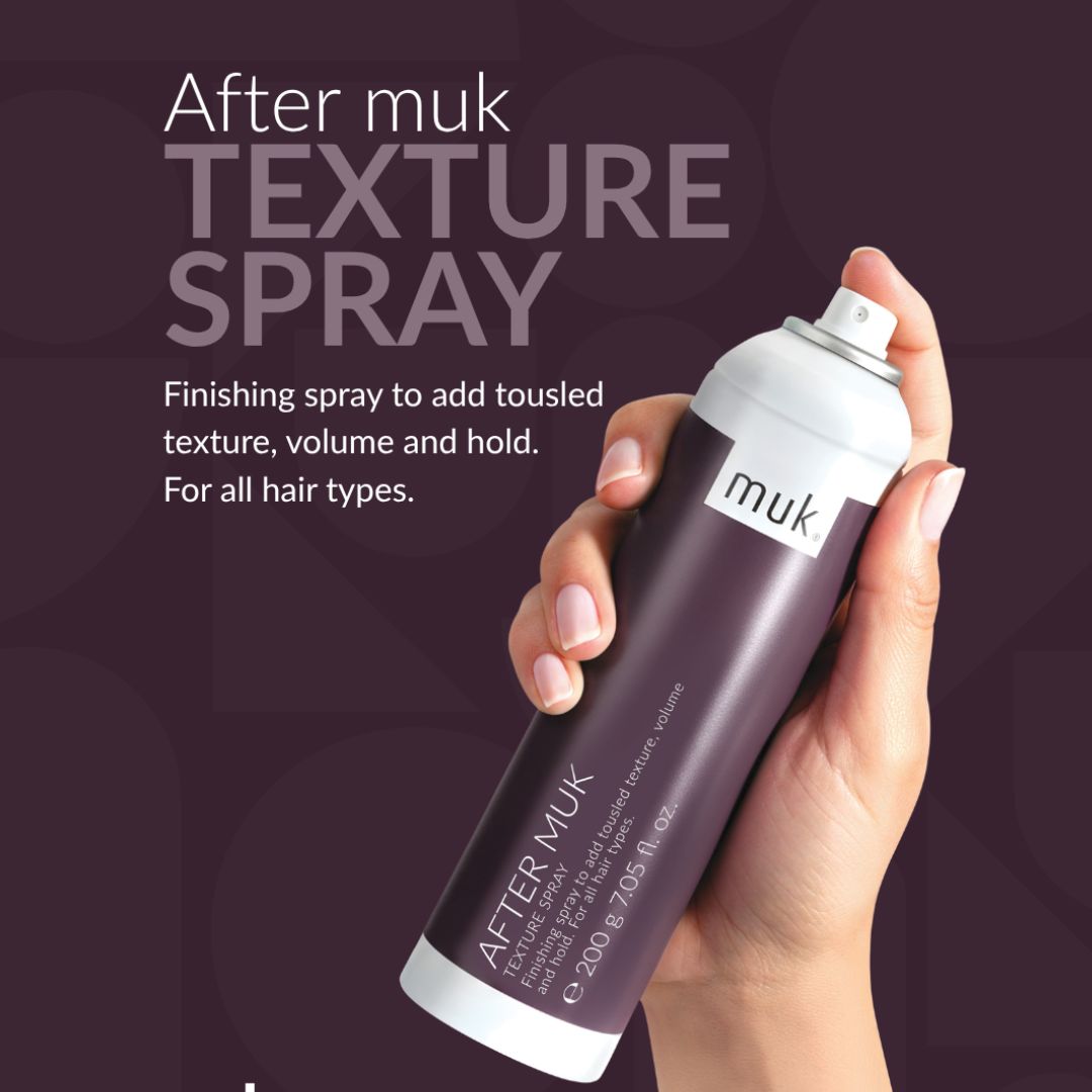 Hand holding a can of After Muk Texture Spray against a dark background