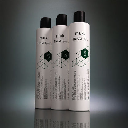 Three bottles of muk. Treat Plus conditioner on a gray background