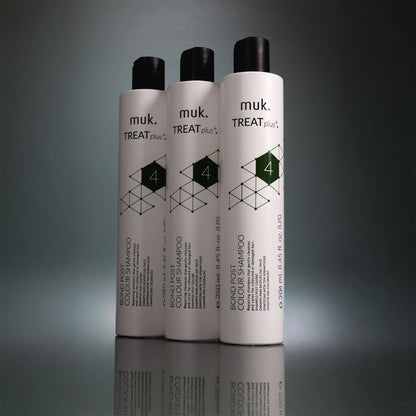 Three bottles of muk. TREAT plus+ shampoo on a reflective surface with a dark background