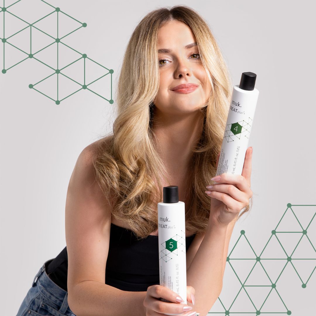 Woman holding muk hair care products against a geometric patterned background