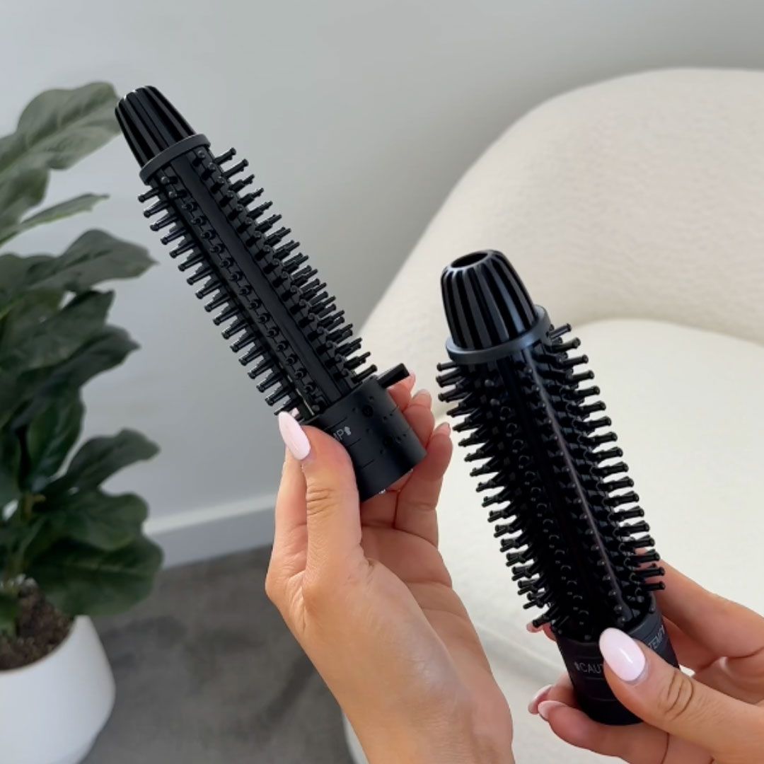 Two black hair styling tools held by hands against a neutral background